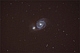 WIR.Gdy w 1845 roku Lord Rosse skierował swój wielki teleskop na ten obiekt, jego oczom ukazał się zagadkowy wir. Nie mając pojęcia co widzi, dokonał odkrycia spiralnej struktury odległej galaktyki. Pełne gracji ramiona spiralne galaktyki M-51 Wir dały jej status ikony i wyrobiły pozycję pokazowego eksponatu nocnego nieba. Galaktyka Wirowa w dramatyczny sposób pokazuje nam także zderzenie dwóch tego typu obiektów. Około 70 milionów lat temu, jej sąsiadka NGC-5195 - ta mniejsza po lewej, otarła się o spirale M-51. Końcowym losem zespołu tych galaktyk, będzie ich ostateczne połączenie za około 1 do 2 miliardów lat. Wir odległy jest od nas o 37 milionów lat świetlnych. Polecam go posiadaczom większych teleskopów. Spirale widoczne są już na ciemnym niebie przez instrumenty o średnicy obiektywu 20 cm. Parametry:2010.04.17.23:01-00:03CWE.Reflektor Newtona 250/1520 + N.D300, w ognisku głównym. Exp.6x250sek, ISO1600.